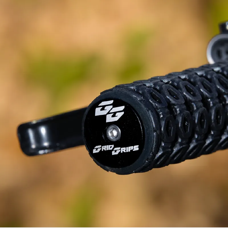 Close-up of the end of a GridGrips grip on a handlebar, its end face printed with the GG logo