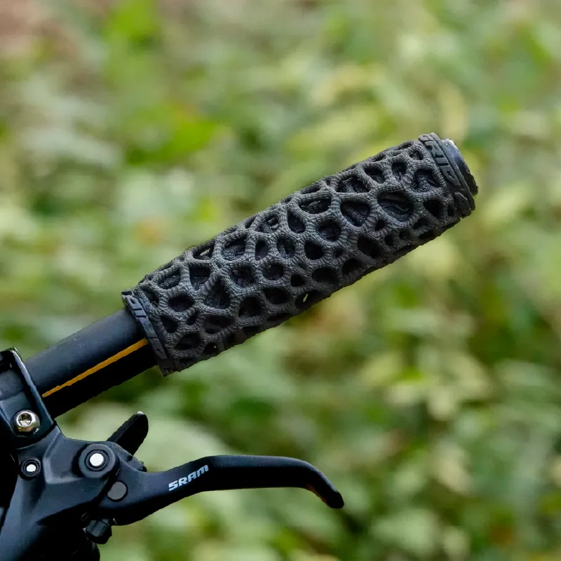 An ExoGrip fitted to a mountain bike handlebar, with green foliage behind