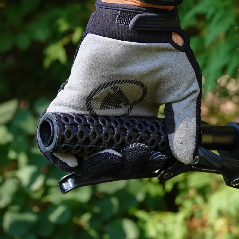 A hand in a grey riding glove gripping a HexGrip on a mountain bike handlebar